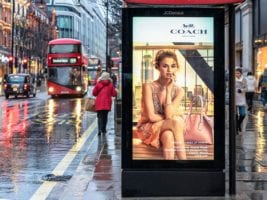 An outdoor bus shelter advertisement on a pavement in London